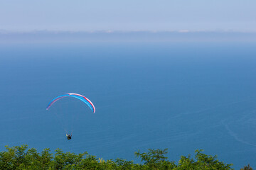 Paraglider in the blue sky and sea. The sportsman flying on a paraglider.