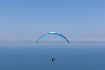 Paraglider in the blue sky and sea. The sportsman flying on a paraglider.