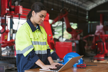 Female engineer worker working with laptop computer for maintenance robot arm system welding at...