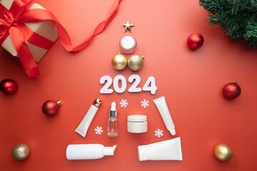Christmas tree made of skincare products and baubles with 2024 number and gift box on red...