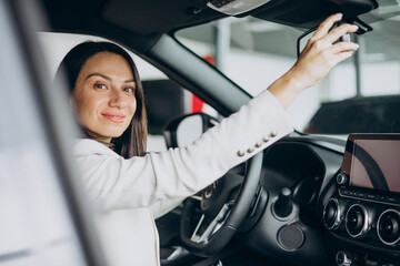 Woman sitting in her new car in a car showroom