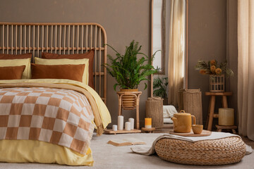 Warm composition of cozy living room interior with stylish bed, yellow bedding, braided pouf,...
