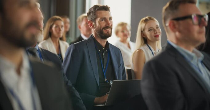 Caucasian Man Sitting in a Crowded Auditorium at an International Conference. Professional Using Laptop Computer. Innovative Presentation Concept: Technology, Science, Health, Mindfulness, Business.
