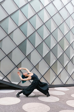 Young dancer bending over backwards in front of modern building