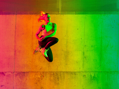 Active woman umping near neon colored wall