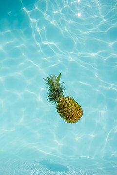 Pineapple floating on water in swimming pool