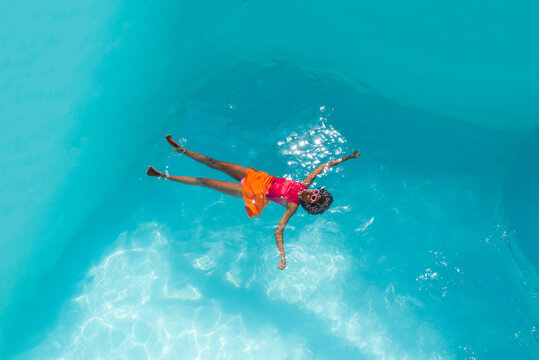 Young woman wearing sunglasses swimming in pool