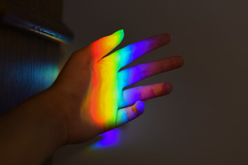 hand holding a prism rainbow effect on a wall colorful light science 