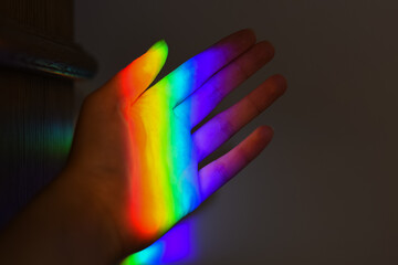 hand holding a prism rainbow effect on a wall colorful light science 