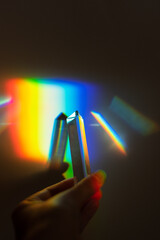 hand holding a prism rainbow effect on a wall colorful light science 