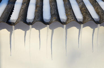 The gutters are filled with an ice dam and large icicles hanging from the roof of the brick building. Winter is coming soon.