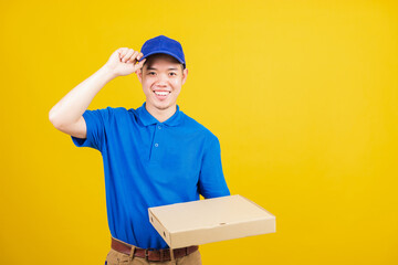 Portrait excited delivery service man standing he smile wearing blue t-shirt and cap uniform hold give food order pizza cardboard boxes looking to camera, studio shot isolated on yellow background