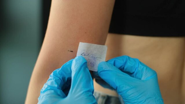 Tattoo artist transferring tattoo stencil on arm. Tattooist preparing skin before tattooing in studio. Body art concept close up