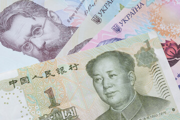one Chinese yuan banknote lying on Ukrainian hrivnya banknotes