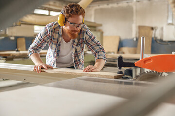 Professional carpenter cutting wooden board at sawmill carpentry manufacturing . Sawing machine
