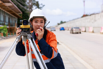 Engineer use theodolite equipment for route surveying to build a bridge across the intersection to...