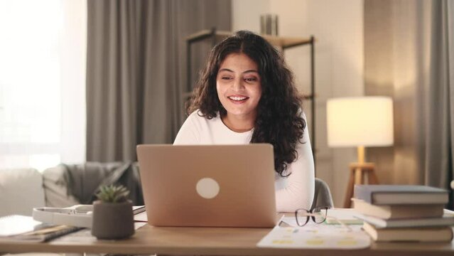 Portrait of beautiful young woman having video call conference meeting interview by computer at home Confident curly female talking on working conversation having distance remote job indoors