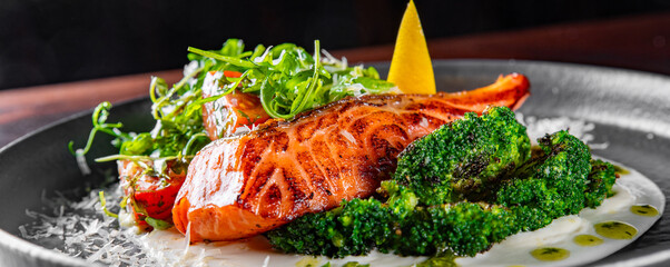 Fried salmon fish with creamy sauce, broccoli and salad