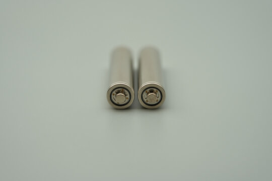 The head of an AAA 1.2V rechargeable battery with the outer casing removed, gray background