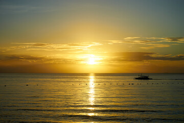 A sunrise over the sea of Matcan Island in the Philippines with a boat floating on the sea