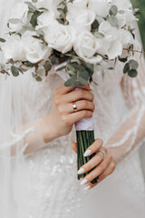The bride in an elegant dress and veil poses with a bouquet. Wedding portrait.
