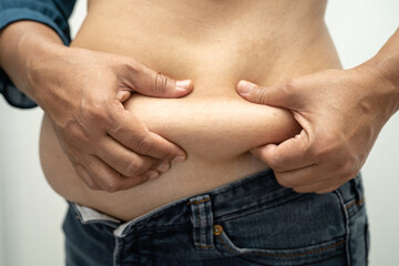 Naklejka premium Overweight Asian woman show and use hand to squeeze fat belly.
