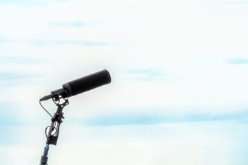 Fototapeta premium Shotgun microphone without protect isolated on sky background. mic on stick for clear professional sound