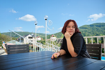 Pretty girl relaxing on resort in Carpathian mountains. Front view of young female sitting in chair...
