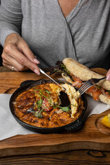 a delicious breakfast omelette with tomato and greens on a wooden table and a sandwich 