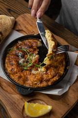 a delicious breakfast omelette with tomato and greens on a wooden table and a sandwich 