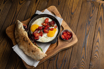 delicious breakfast with egg and sausages in a frying pan on a wooden table