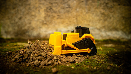 South Minahasa, Indonesia - January 3, 2023: a yellow bulldozer toy is leveling the ground - obrazy, fototapety, plakaty