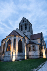Church of Notre-Dame-de-l'Assomption, a Catholic parish church located in Auvers-sur-Oise, in the French department of Val-d'Oise, France. The church was painted by Vincent van Gogh. Sunset, blue sky