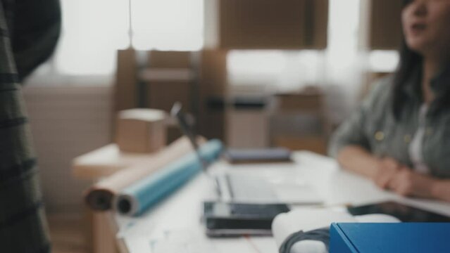 Female post office clerk working on laptop, giving parcel to customer, shipping