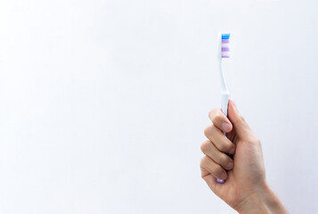 Hand holding a toothbrush on gradient background. After some edits.