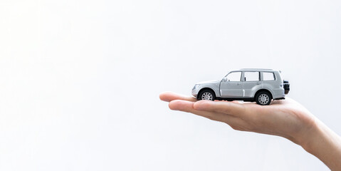 Hand holding a toy car isolated on gradient background. After some edits.