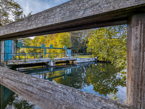 Stauwehr der Innerste bei Sarstedt gerahmt durch ein Gel&auml;nder mit Spiegelung im Wasser
