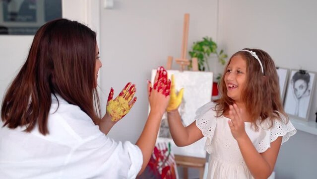 Teacher At Art School Playing Children in Art Class with Acrylic Paint. Girl with painted arm hands. Woman teaches child to create and work with acrylic paint.