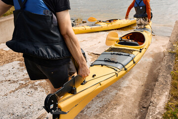 High angle view of men carrying kayak at coast