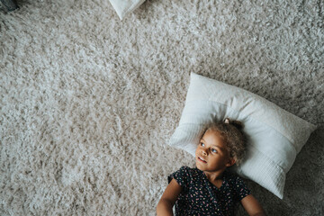 Girl lying on pillow relaxing on carpet