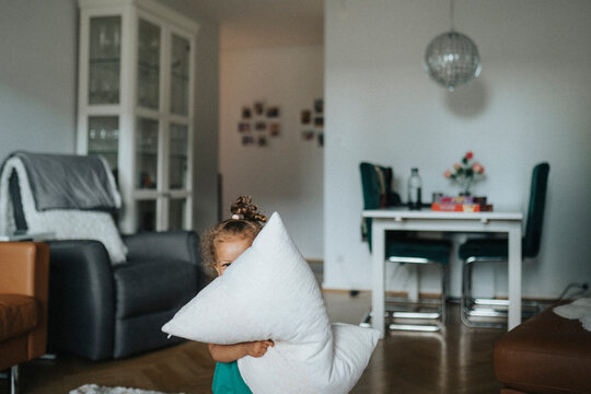 Playful girl peeking from behind pillow