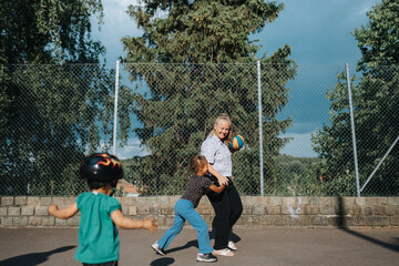 Mother and daughters playing basketball outdoors