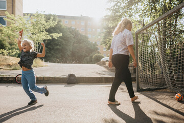 Mother and daughter playing football outdoors