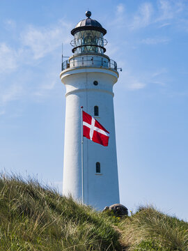 Low angle view of lighthouse with Danish flag in foreground