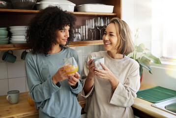 Breakfast, lgbtq and couple in morning with drink together for bonding, love and conversation. Happy, lesbian and women with juice and coffee for healthy relationship, nutrition and chat for romance