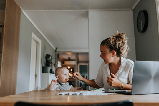 Multitasking mother taking care of baby and working from home - Powered by Adobe