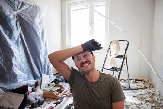 Man in protective eyeglasses renovating room at home