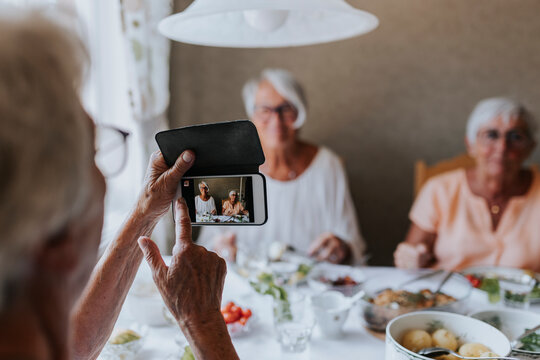 Senior women having picture taken while having meal together