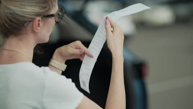 Shopper after grocery store . Female checking paper receipt  