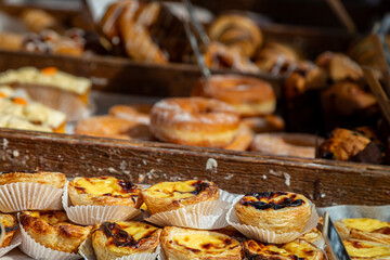 A display of custard tarts and doughnuts for sale on a stall